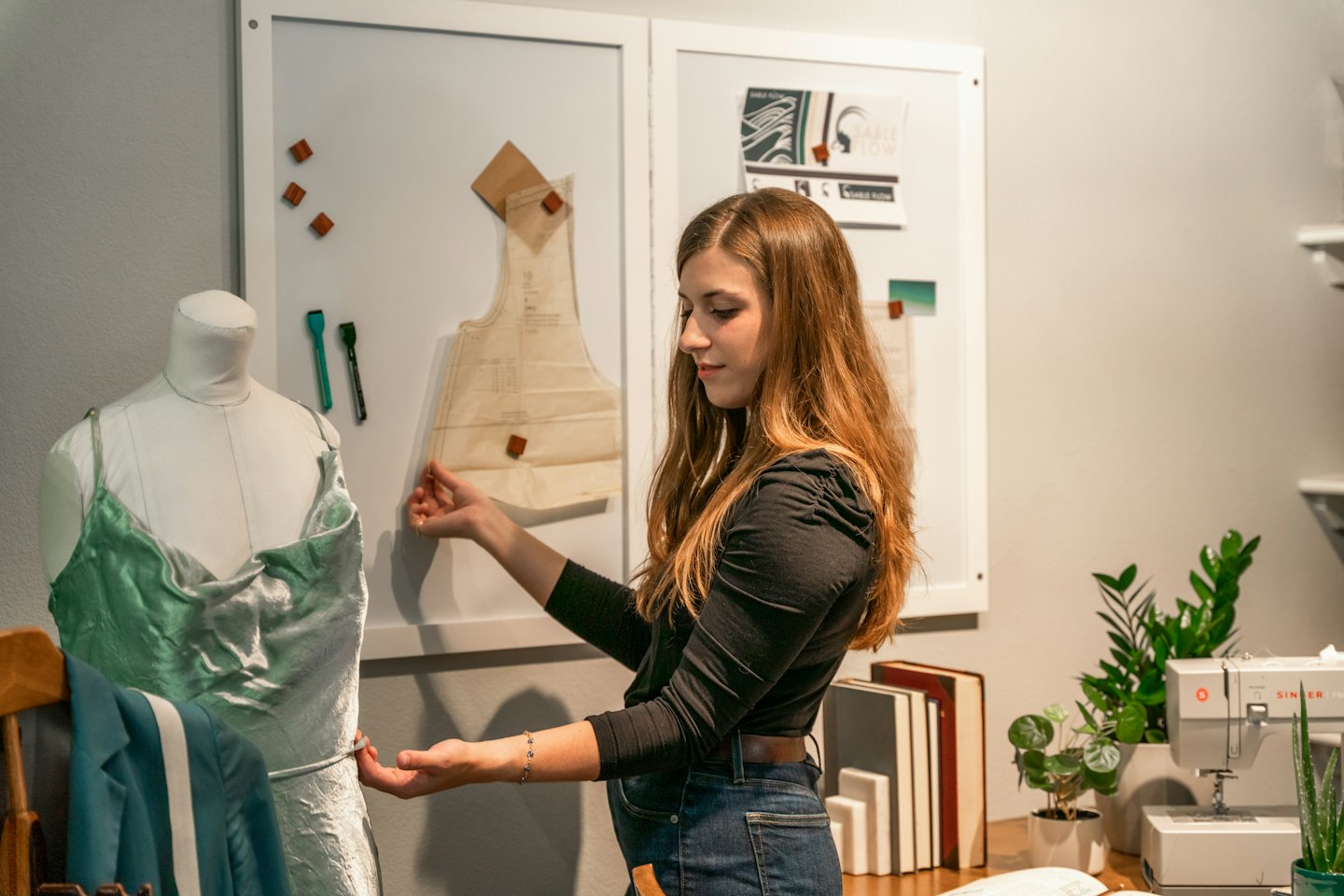 Fashion designer adjusts a satin dress on a mannequin in a studio.