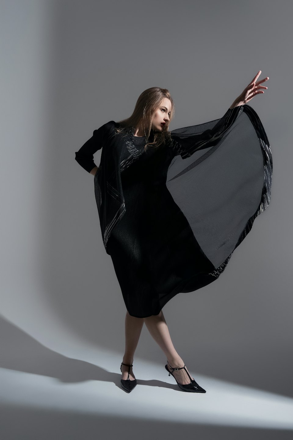 Woman in a black dress with silver accents posing dynamically.